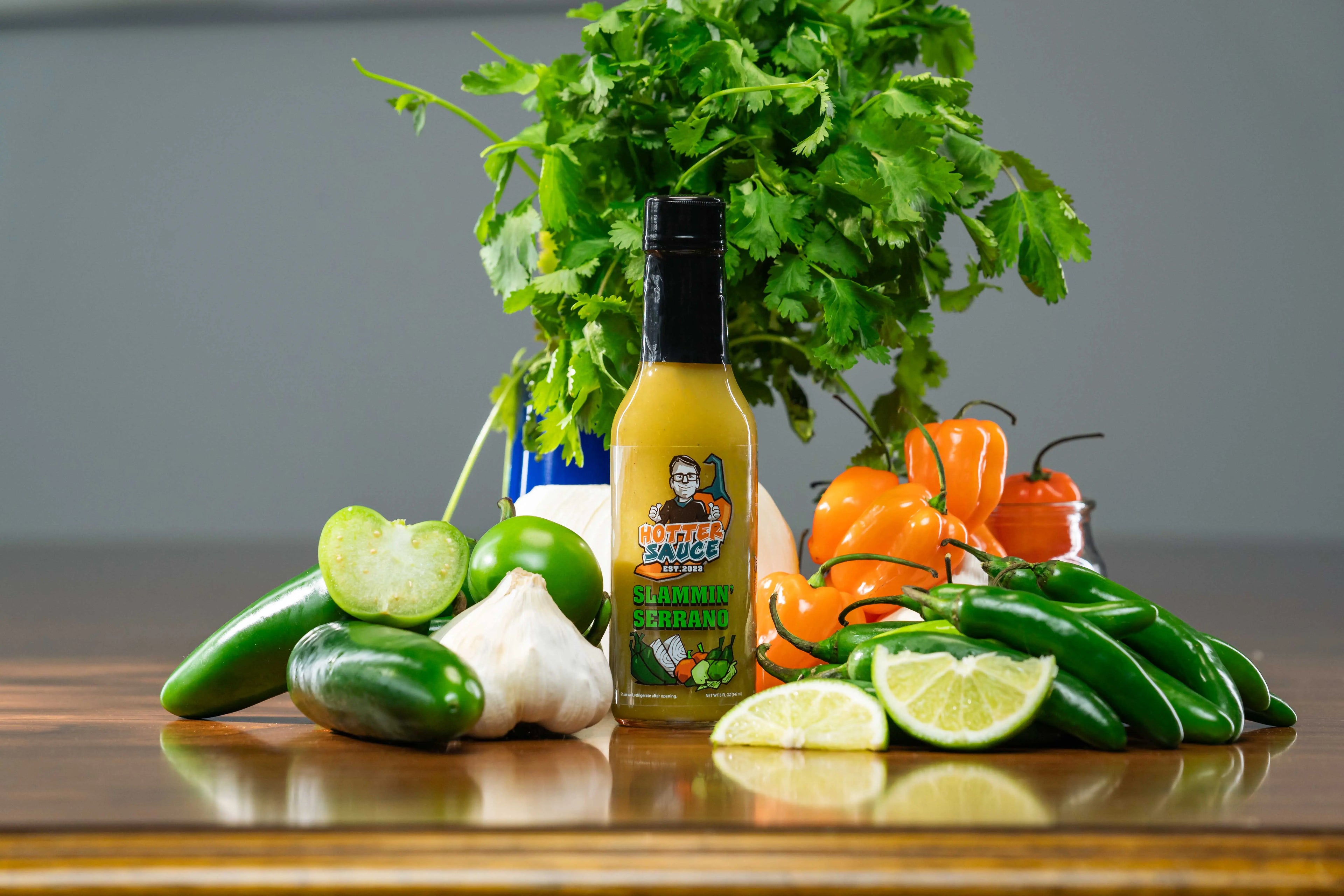 Slammin Serrano hot sauce bottle with ingredients on a wooden surface